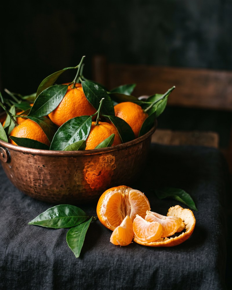 Mandarine u bakrenoj zdjeli na tamnom lanu